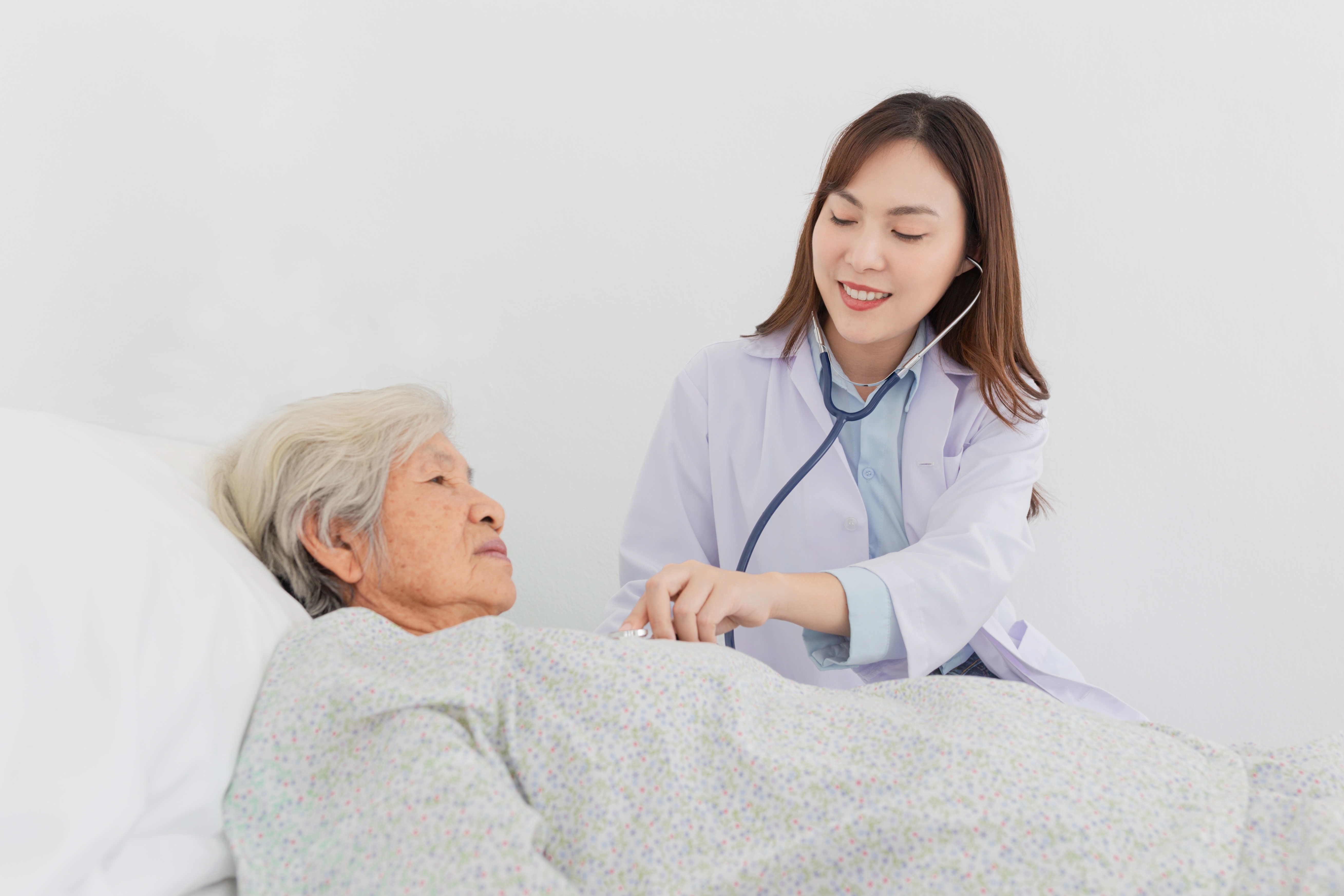 Asian,Female,Doctor,Examining,Elderly,Patient,With,Stethoscope,In,Hospital